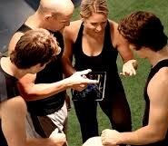 Quatre personnes en tenue de sport regardant une tablette