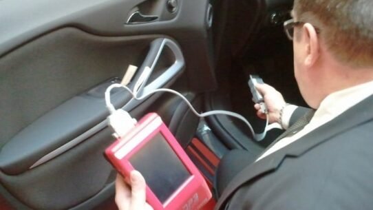 Technicien effectuant un diagnostic auto avec un outil électronique