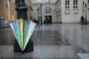 Parapluie aux reflets irisés posé contre un lampadaire