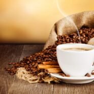 Tasse de café fumant avec des grains et des bâtons de cannelle