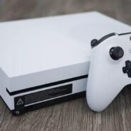 Console de jeu blanche avec une manette sur une table en bois