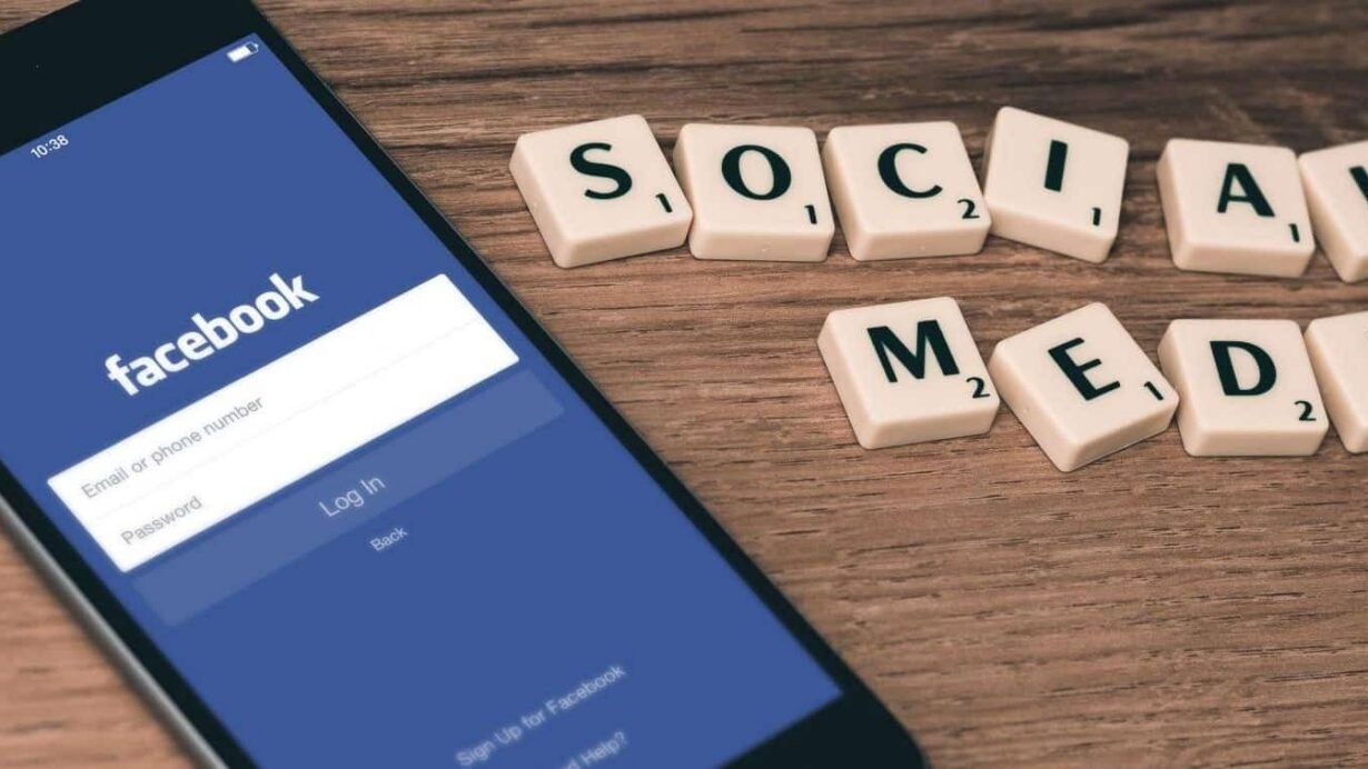 Smartphone affichant Facebook à côté de lettres formant 'Social Media'