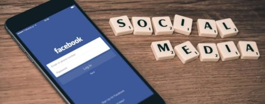 Smartphone affichant Facebook à côté de lettres formant 'Social Media'