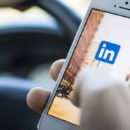 Main tenant un smartphone affichant le logo LinkedIn