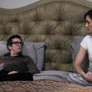 Deux personnes discutant sur un lit dans une chambre