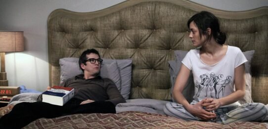 Deux personnes discutant sur un lit dans une chambre