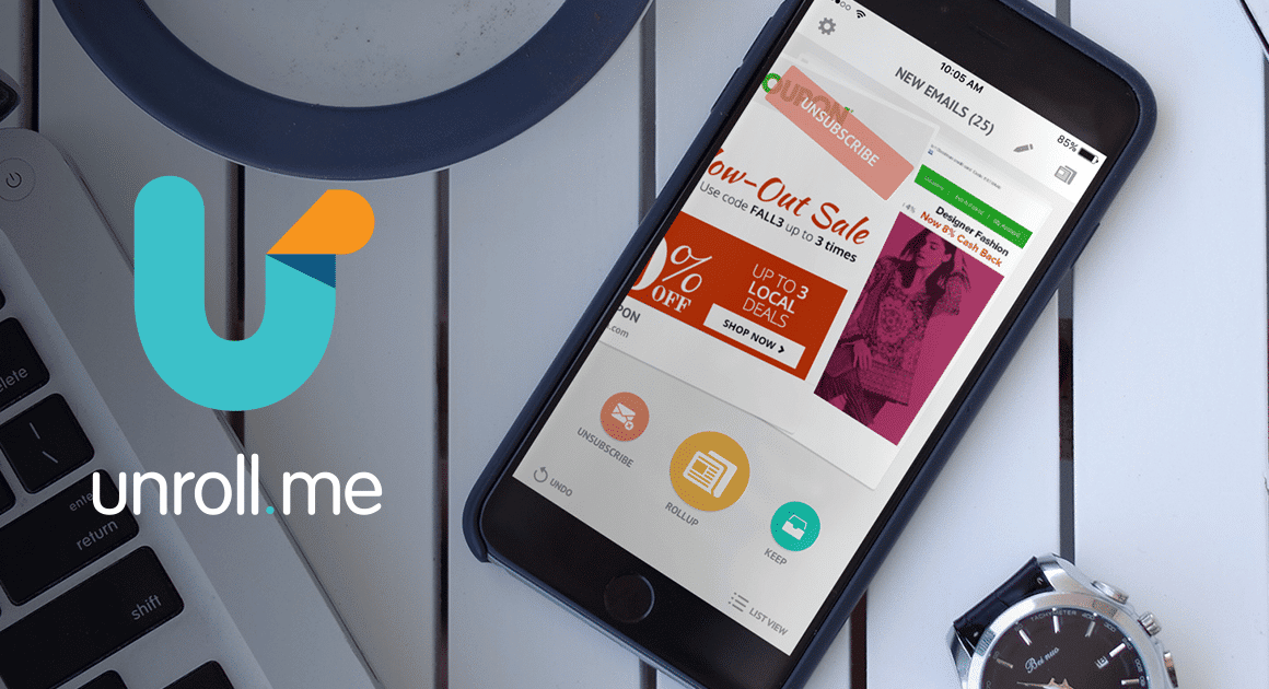 Application Unroll.me ouverte sur un smartphone à côté d'un ordinateur