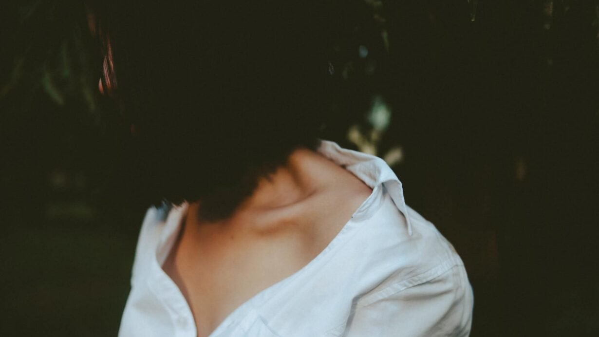 Femme de profil en chemise blanche, fond sombre