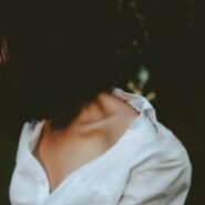 Femme de profil en chemise blanche, fond sombre