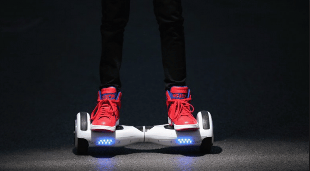 Personne portant des baskets rouges sur un hoverboard blanc