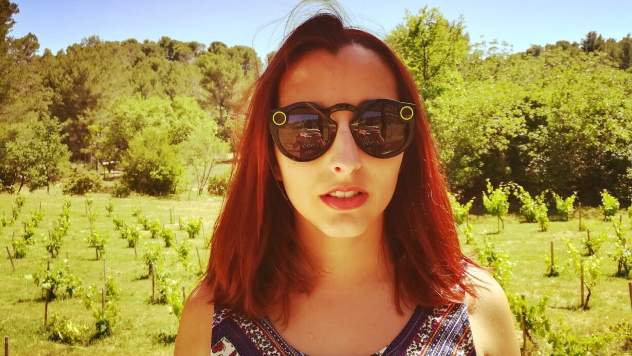 Femme portant des lunettes connectées devant un vignoble ensoleillé