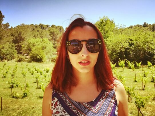 Femme portant des lunettes connectées devant un vignoble ensoleillé