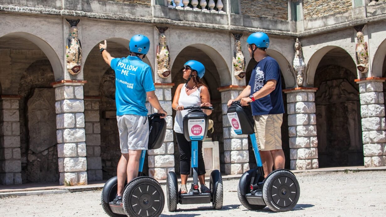 Trois personnes en gyropode devant un bâtiment ancien