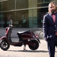 Homme en costume debout à côté d'un scooter électrique