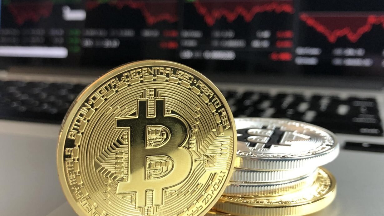 Pièces de bitcoin devant un écran de marché boursier