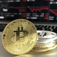 Pièces de bitcoin devant un écran de marché boursier