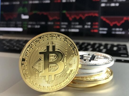 Pièces de bitcoin devant un écran de marché boursier