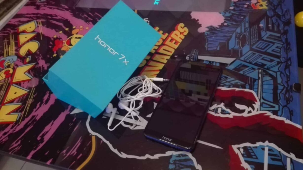 Smartphone Honor 7X avec écouteurs et boîte sur fond de jeux rétro