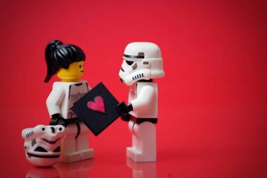 Figurines LEGO échangeant une carte avec un cœur sur fond rouge