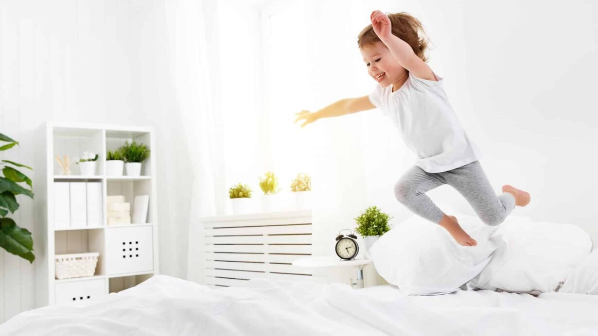 Enfant sautant sur un lit dans une chambre lumineuse