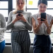 Quatre personnes regardant leurs smartphones devant une fenêtre