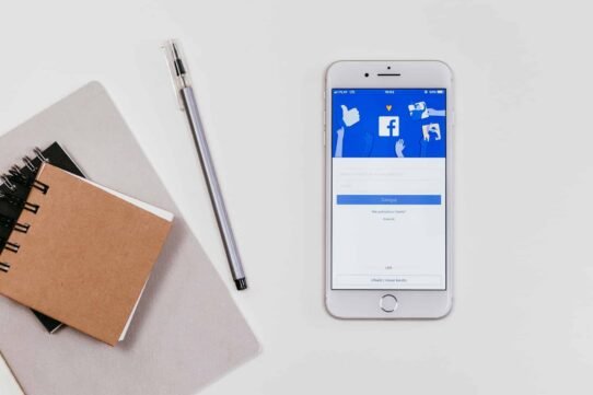 Smartphone affichant Facebook avec carnet et stylo