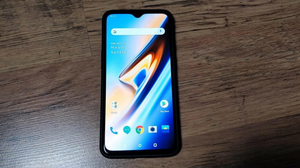 Smartphone avec écran allumé posé sur une table en bois