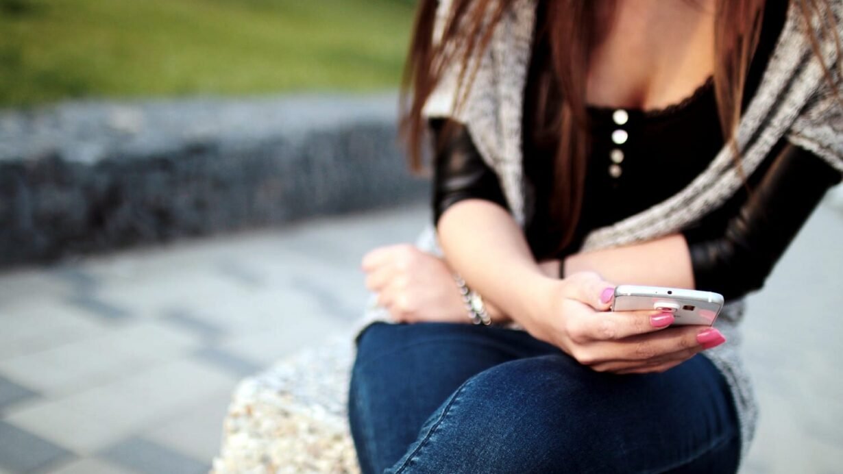 Femme assise utilisant un smartphone en plein air