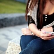 Femme assise utilisant un smartphone en plein air