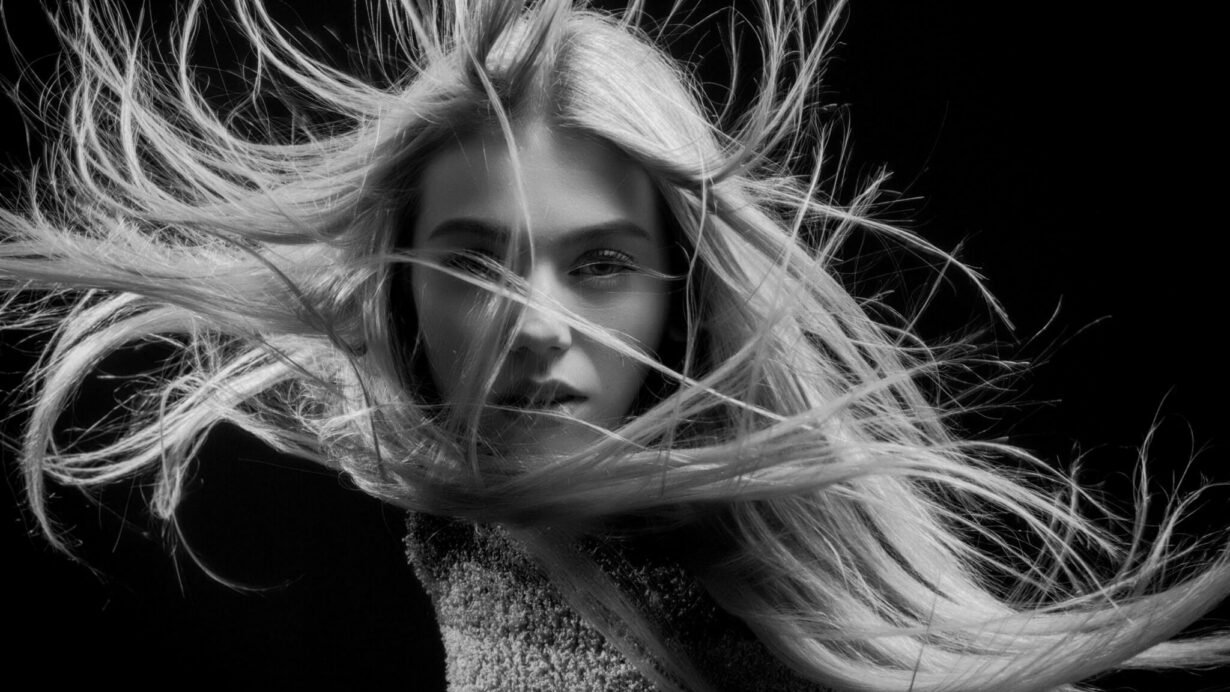 Femme en noir et blanc avec cheveux flottants face à la caméra
