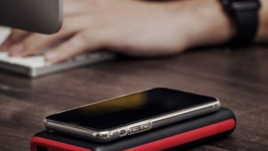 Smartphone posé sur un chargeur externe rouge et noir sur un bureau