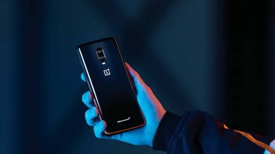 Smartphone noir tenu en main dans une lumière bleue