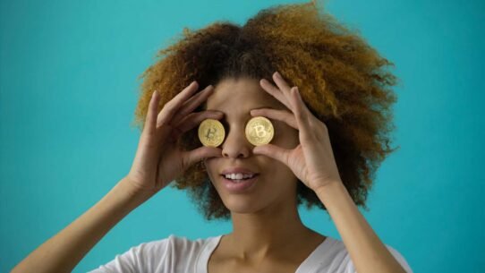 Femme tenant des bitcoins devant ses yeux sur fond bleu