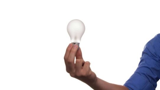 Main tenant une ampoule sur fond blanc