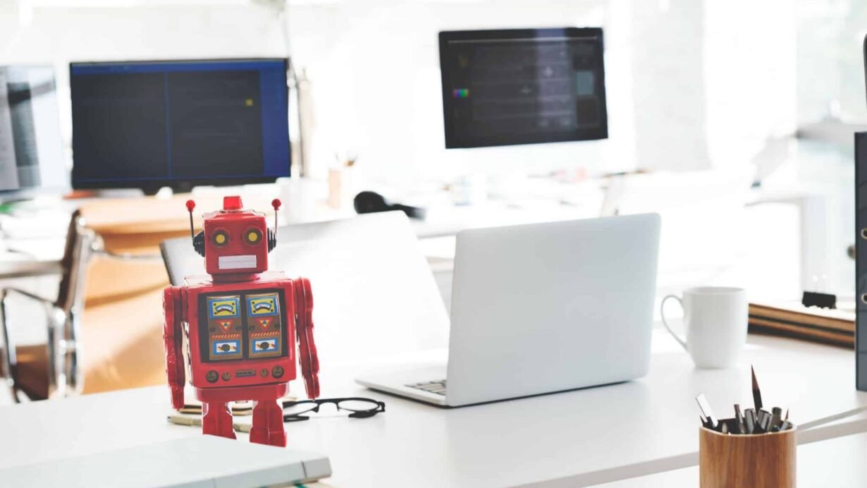 Robot rouge sur un bureau moderne avec des ordinateurs