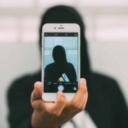 Personne masquée prenant un selfie avec un smartphone