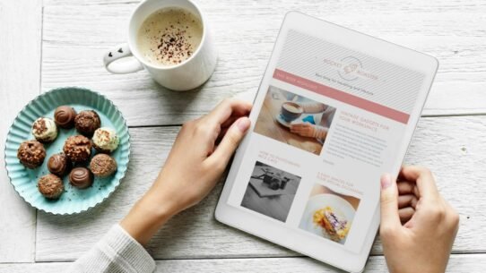 Personne lisant une tablette avec café et chocolats sur table