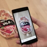 Main tenant un smartphone scannant une pizza emballée