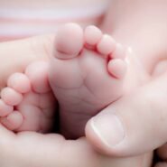 Pieds de bébé tenus délicatement par des mains adultes
