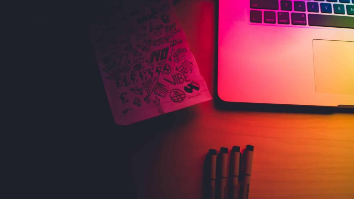 Carnet de croquis et ordinateur portable dans une lumière colorée