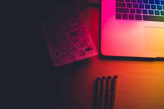 Carnet de croquis et ordinateur portable dans une lumière colorée