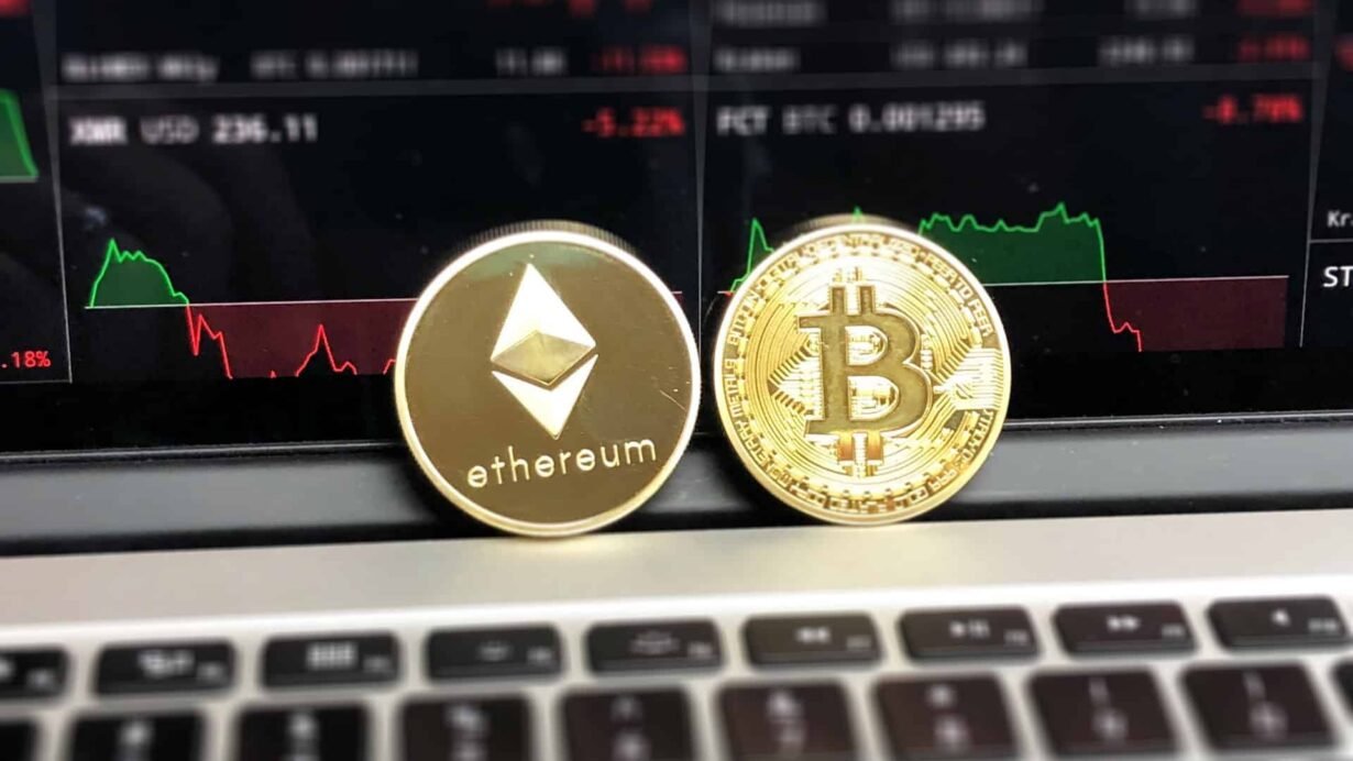 Pièces Bitcoin et Ethereum devant un graphique financier