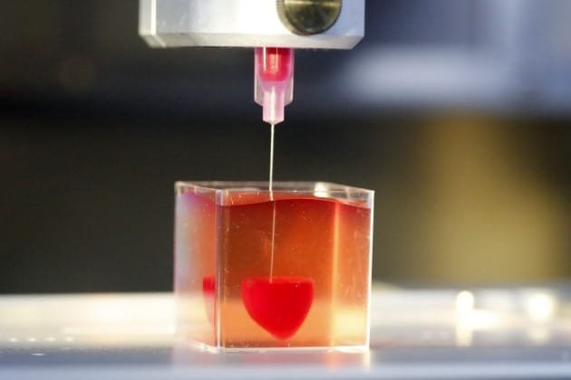 Imprimante 3D créant un cœur rouge dans un gel transparent