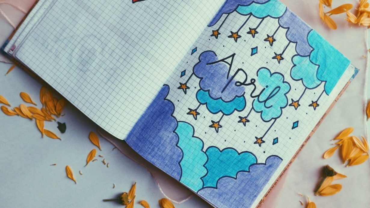 Page de carnet avec nuages bleus, étoiles orange et texte avril.
