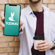 Homme montrant un smartphone avec l'application Tookki