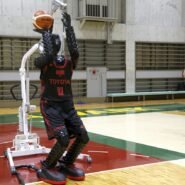 Robot jouant au basket dans un gymnase avec un entraîneur à côté