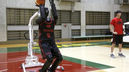 Robot jouant au basket dans un gymnase avec un entraîneur à côté
