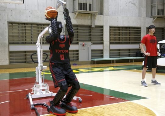 Robot jouant au basket dans un gymnase avec un entraîneur à côté