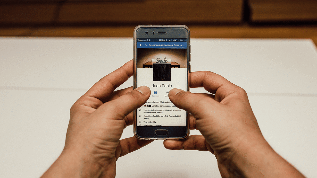 Main tenant un smartphone affichant un profil de réseau social