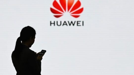 Silhouette d'une femme avec smartphone devant le logo Huawei